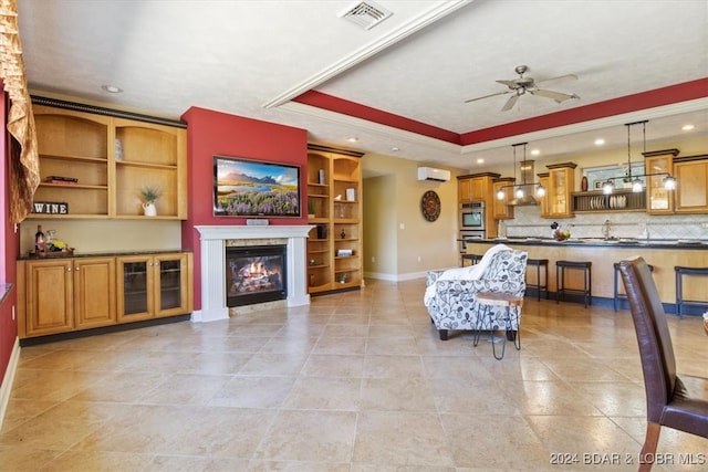 tiled living room with a fireplace, built in shelves, a tray ceiling, ceiling fan, and an AC wall unit