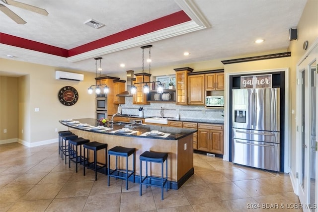 kitchen featuring a wall mounted AC, a breakfast bar area, appliances with stainless steel finishes, a kitchen island with sink, and decorative backsplash