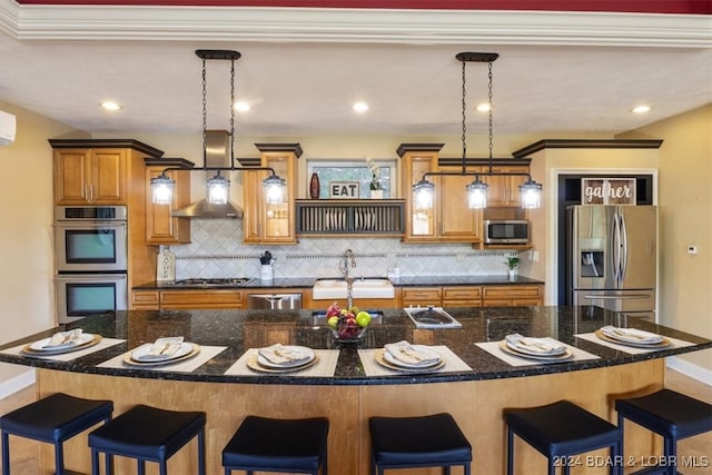 kitchen featuring appliances with stainless steel finishes, decorative light fixtures, an island with sink, and backsplash