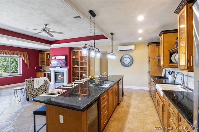 kitchen featuring a wall mounted AC, a kitchen breakfast bar, sink, ceiling fan, and a center island with sink