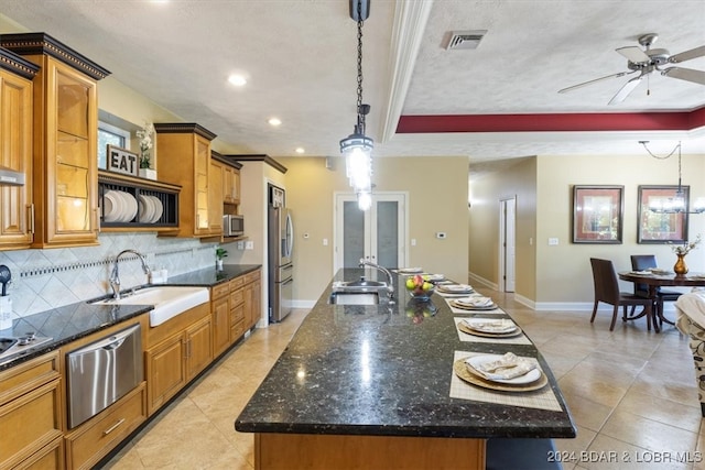 kitchen featuring ceiling fan, sink, decorative light fixtures, and a kitchen island with sink