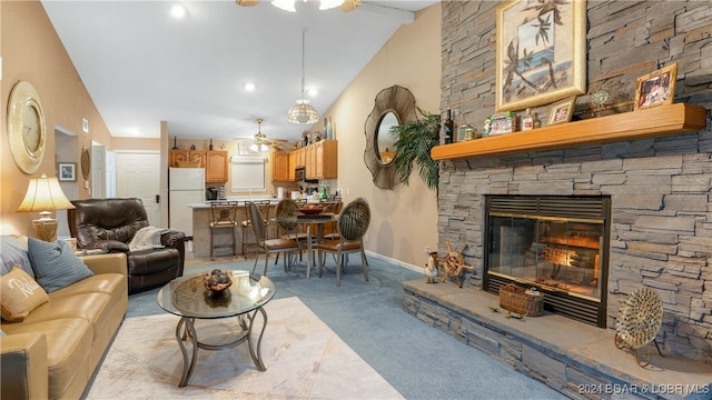 carpeted living room with ceiling fan, vaulted ceiling, and a stone fireplace