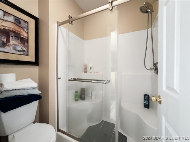 bathroom with a shower with door and toilet