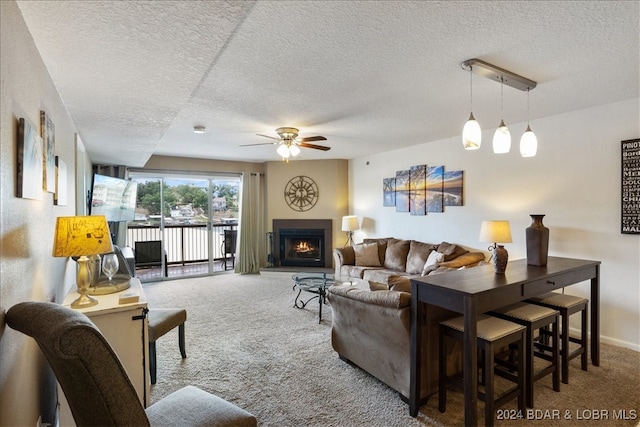 living room featuring a textured ceiling, carpet flooring, and ceiling fan