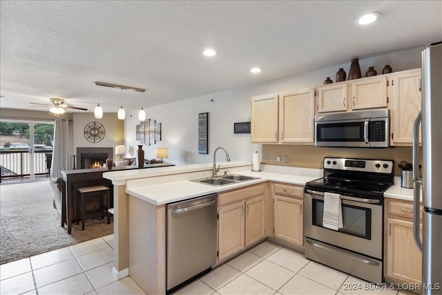 kitchen with light brown cabinetry, appliances with stainless steel finishes, kitchen peninsula, sink, and ceiling fan