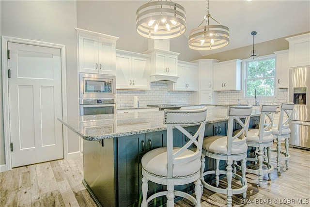 kitchen with white cabinetry, stainless steel appliances, a kitchen island, and hanging light fixtures