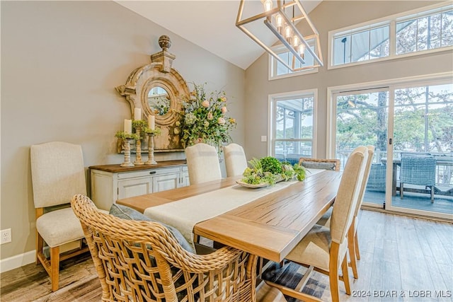 dining room with high vaulted ceiling, an inviting chandelier, and light hardwood / wood-style flooring