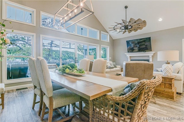 dining space with ceiling fan, high vaulted ceiling, and light hardwood / wood-style floors