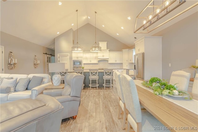 living room featuring a barn door, high vaulted ceiling, and light hardwood / wood-style flooring