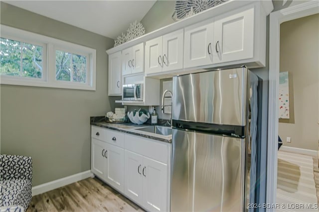 kitchen featuring appliances with stainless steel finishes, light hardwood / wood-style floors, sink, and white cabinets