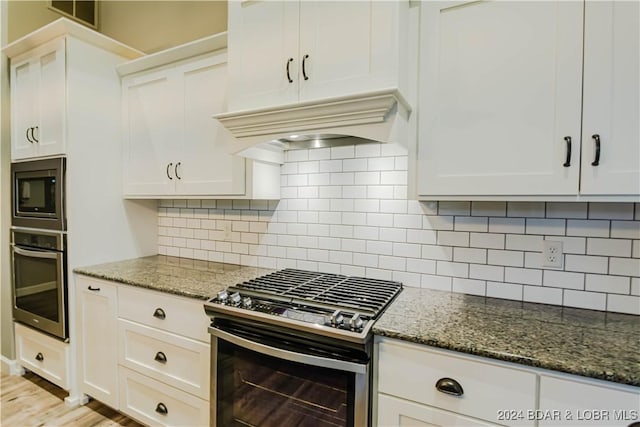 kitchen featuring white cabinetry, premium range hood, and appliances with stainless steel finishes