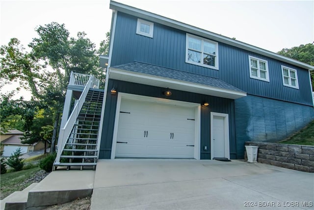 view of front of property with a garage, concrete driveway, roof with shingles, and stairs