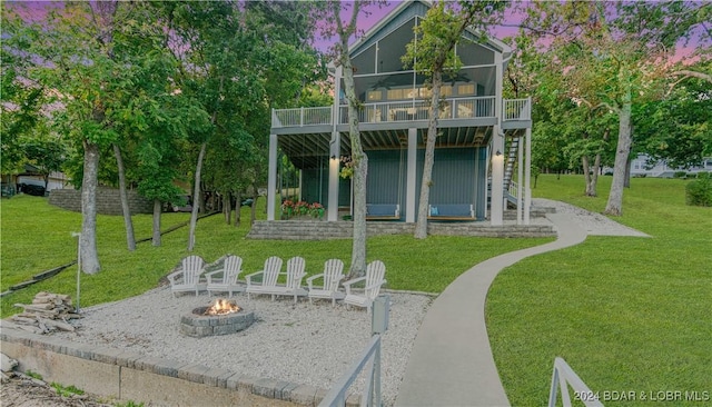 rear view of house with a fire pit, stairway, a sunroom, and a lawn