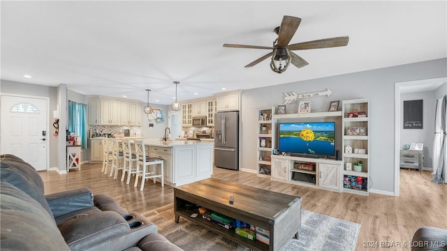 living room featuring ceiling fan, sink, and light hardwood / wood-style floors