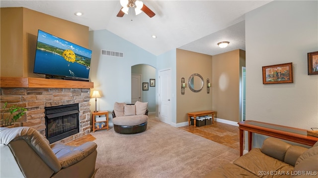 carpeted living room featuring a stone fireplace, lofted ceiling, and ceiling fan