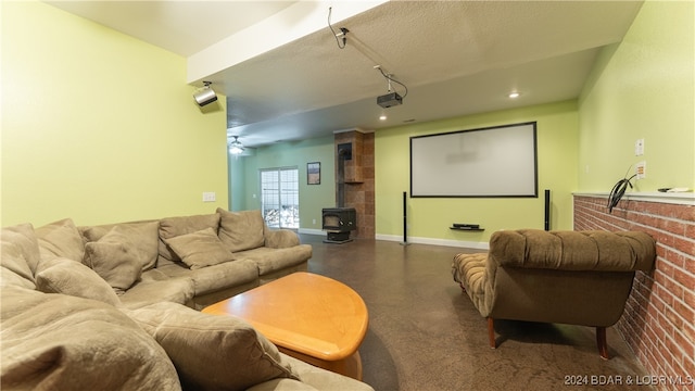 home theater room with a wood stove, ceiling fan, and a textured ceiling