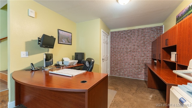 carpeted office space with brick wall and a textured ceiling