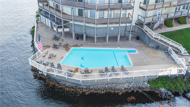 view of swimming pool with a water view and a patio area