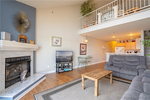 living room featuring high vaulted ceiling, a high end fireplace, sink, and wood-type flooring