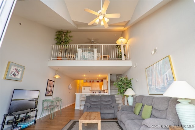 living room featuring ceiling fan, wood-type flooring, and a high ceiling