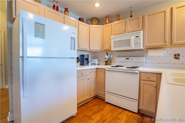 kitchen featuring light wood-type flooring, light brown cabinets, and white appliances