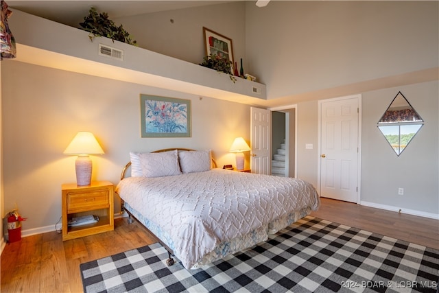 bedroom with high vaulted ceiling and hardwood / wood-style flooring