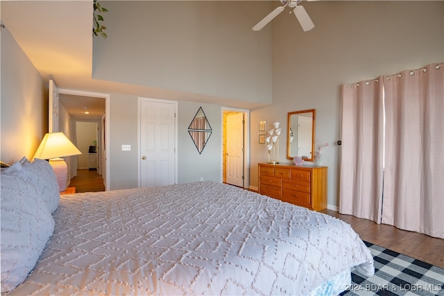 bedroom with ceiling fan, light wood-type flooring, and a high ceiling