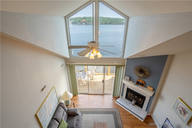 living room featuring lofted ceiling, hardwood / wood-style flooring, ceiling fan, and a water view