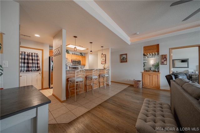 living room featuring a textured ceiling, light hardwood / wood-style flooring, and ceiling fan