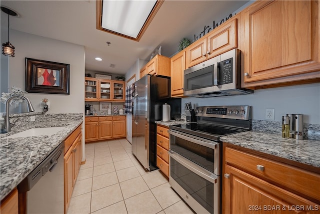 kitchen featuring pendant lighting, light stone counters, sink, and appliances with stainless steel finishes