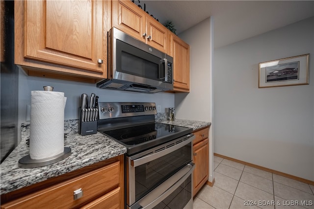 kitchen with light stone countertops, appliances with stainless steel finishes, and light tile patterned flooring