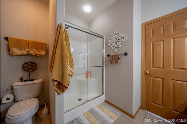 bathroom featuring a shower with door, toilet, and tile patterned flooring