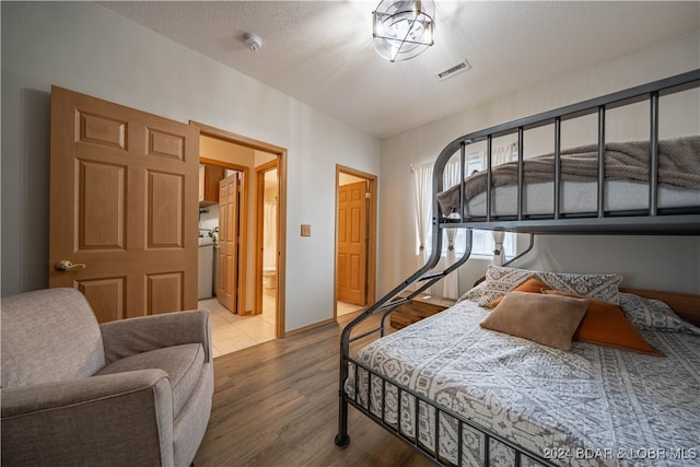 bedroom with a textured ceiling, washer / dryer, and hardwood / wood-style floors