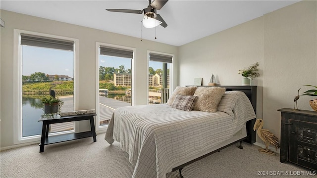 bedroom featuring a water view, light carpet, and ceiling fan