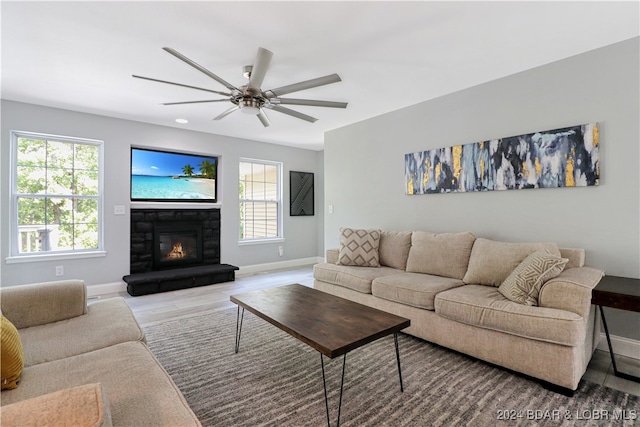 living room featuring a fireplace, plenty of natural light, light hardwood / wood-style flooring, and ceiling fan