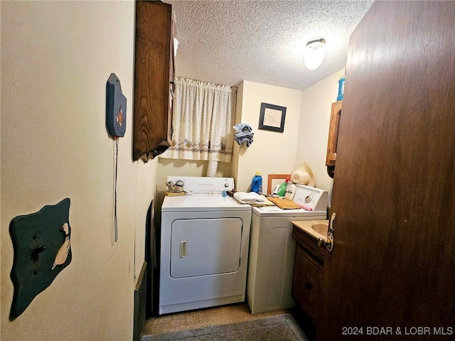 washroom with washer and dryer, cabinets, and a textured ceiling