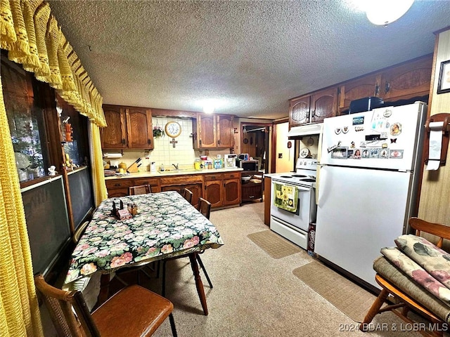 kitchen with light carpet, white appliances, custom range hood, and a textured ceiling