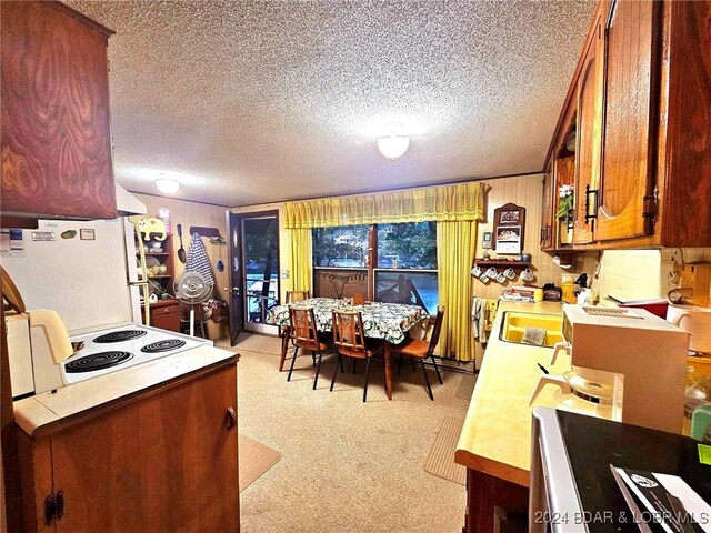 kitchen featuring a textured ceiling, light colored carpet, and white appliances