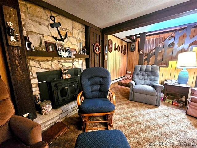 living room featuring a fireplace, a textured ceiling, wood walls, a baseboard radiator, and carpet floors