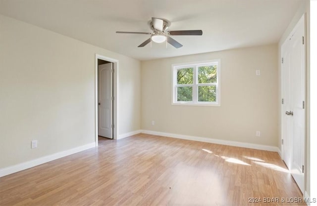 spare room with ceiling fan, baseboards, and light wood-style flooring