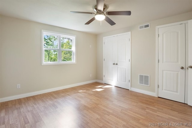 unfurnished bedroom featuring two closets, ceiling fan, and light hardwood / wood-style floors