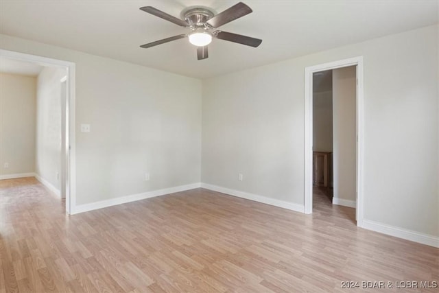 empty room with baseboards, a ceiling fan, and light wood-style flooring