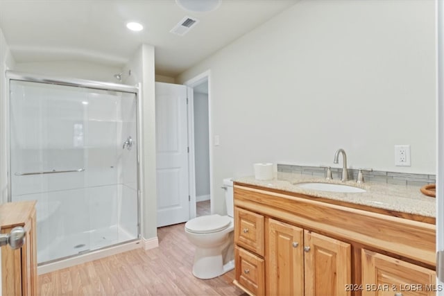 bathroom featuring vanity, toilet, wood-type flooring, and a shower with door