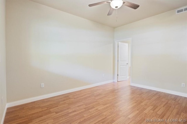 empty room with light wood finished floors, baseboards, a ceiling fan, and visible vents