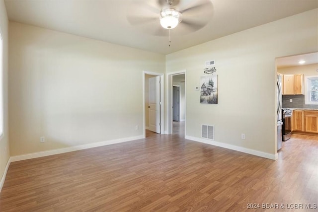 empty room featuring light wood finished floors, baseboards, visible vents, and ceiling fan