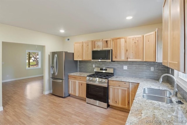 kitchen featuring light brown cabinets, backsplash, appliances with stainless steel finishes, and a sink