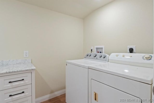 washroom with light wood-type flooring, baseboards, washer and dryer, and cabinet space