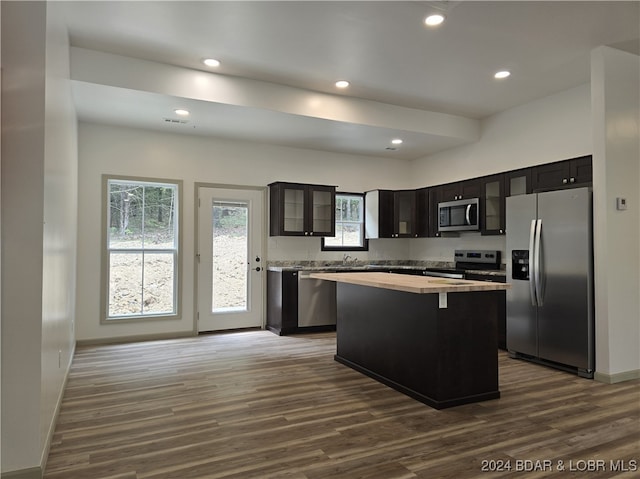 kitchen featuring a kitchen island, appliances with stainless steel finishes, a kitchen bar, dark wood-type flooring, and sink