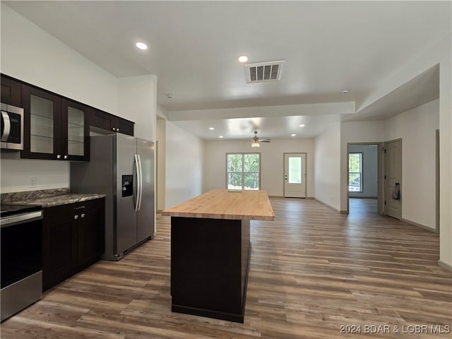 kitchen featuring a kitchen island, wooden counters, stainless steel appliances, and dark wood-type flooring