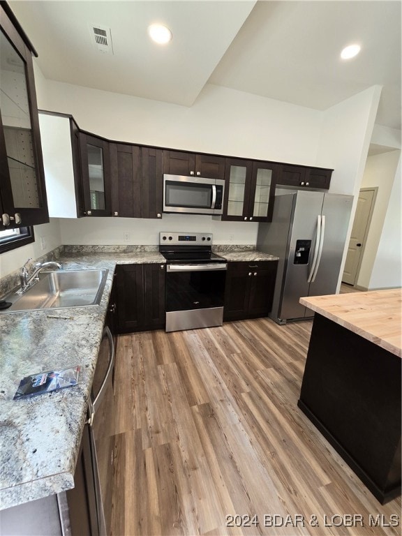 kitchen with sink, appliances with stainless steel finishes, dark brown cabinets, and light hardwood / wood-style floors